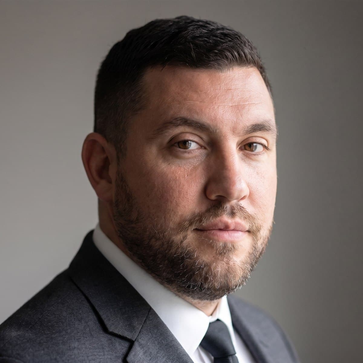 The same man as a professional LinkedIn headshot in a suit and tie