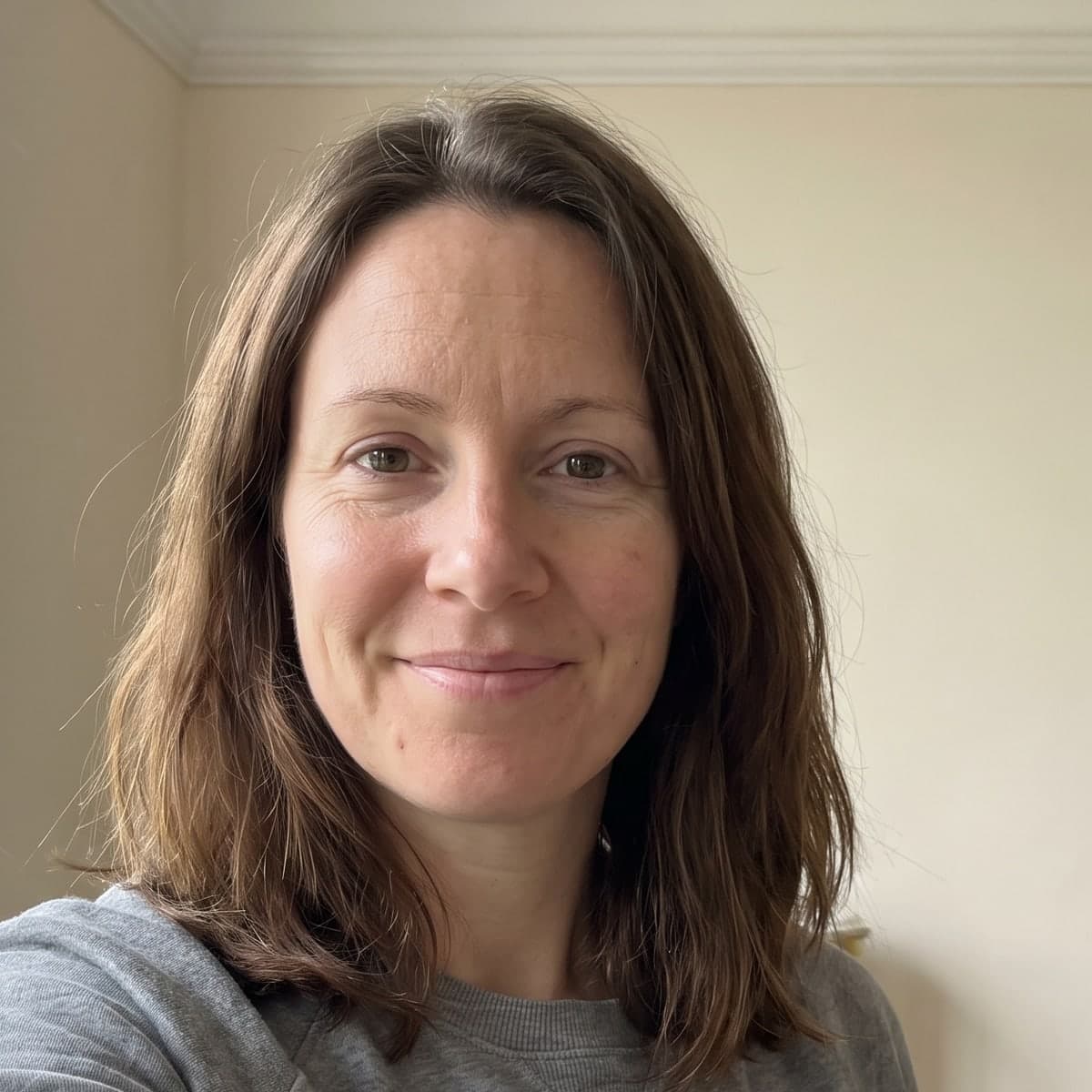 An ordinary phone selfie of a woman in a sweatshirt at home