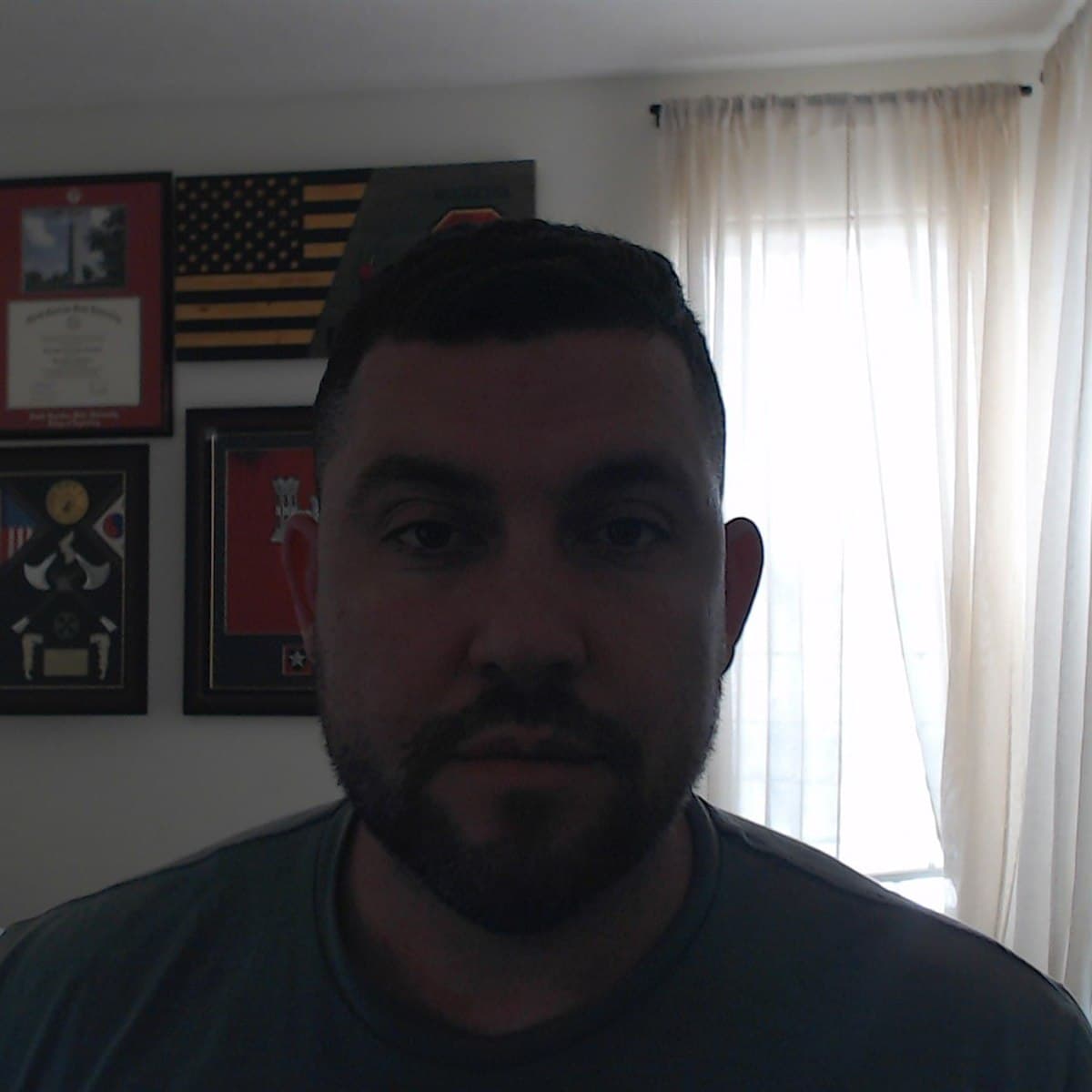 A real, dimly lit webcam selfie of the founder at home in a t-shirt